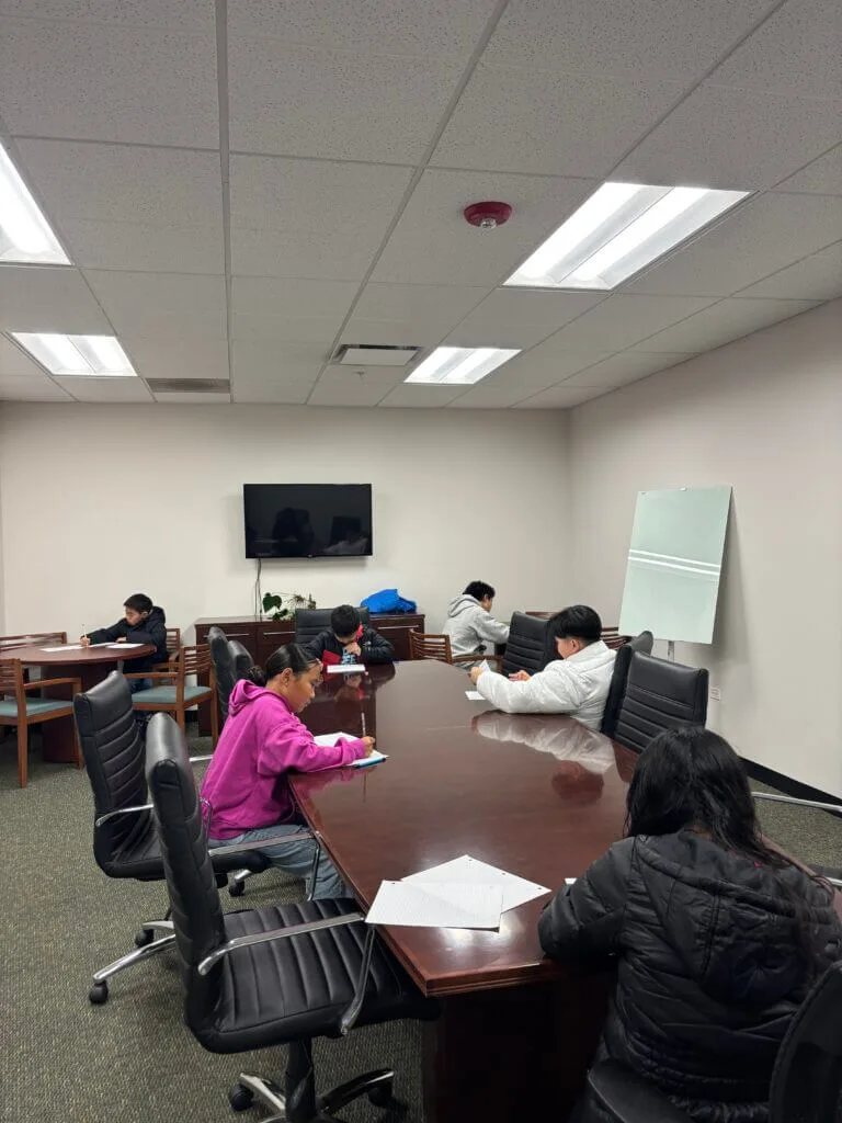 People writing at office conference table.