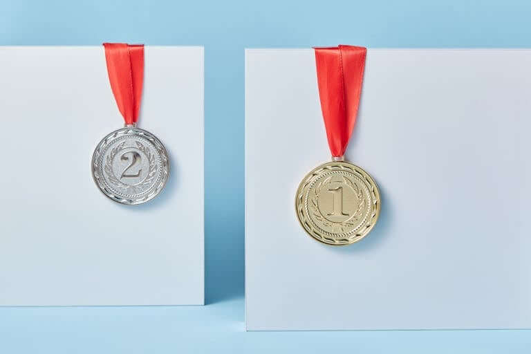Gold and silver medals with red ribbons against a blue backdrop representing achievement and success.